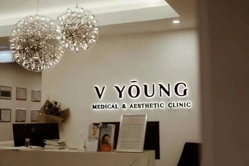 Reception counter under two sparkling starburst chandeliers with the V Young wall sign and framed certificates