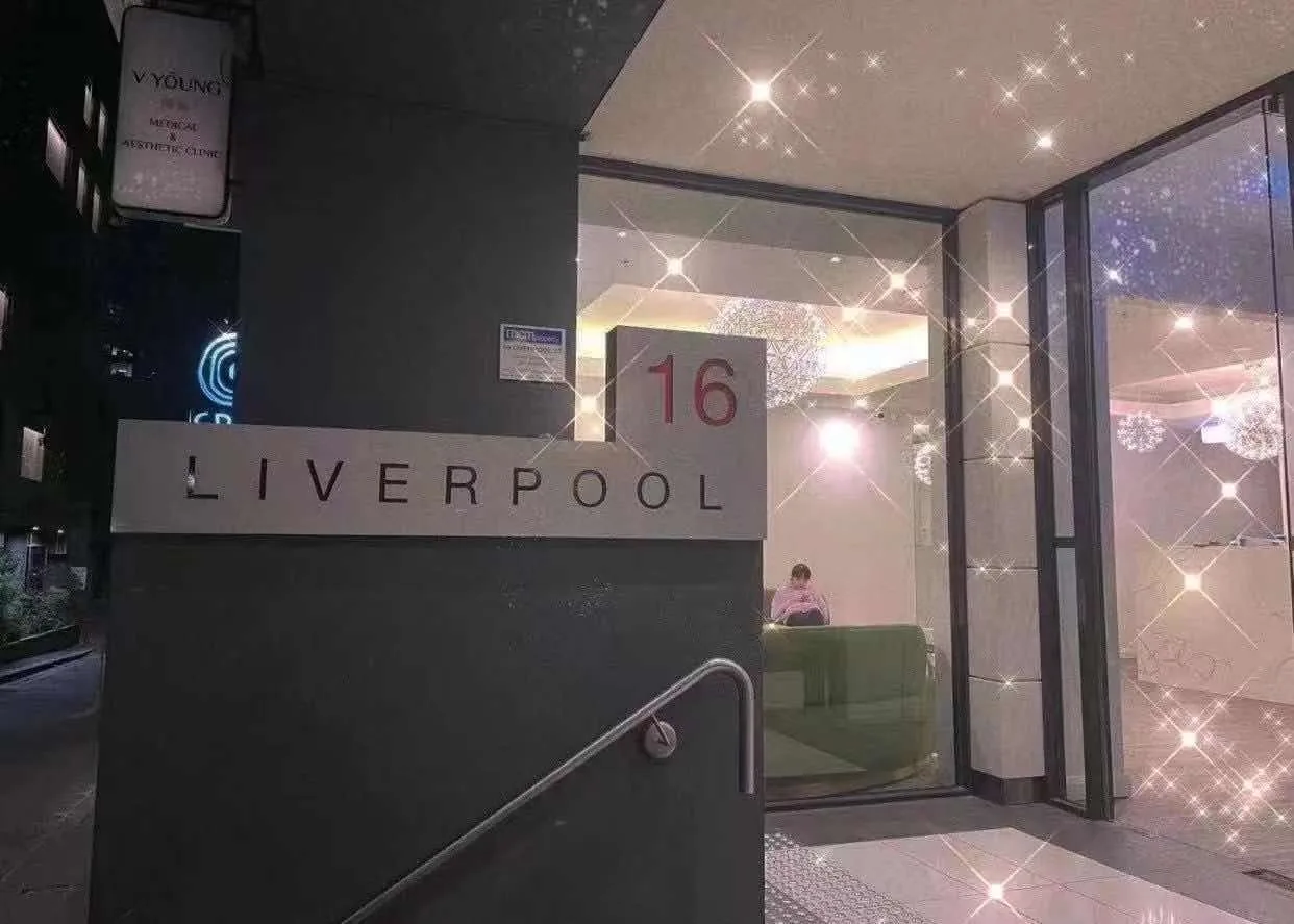 Illuminated night entrance with V Young light-box sign and 16 Liverpool building signage
