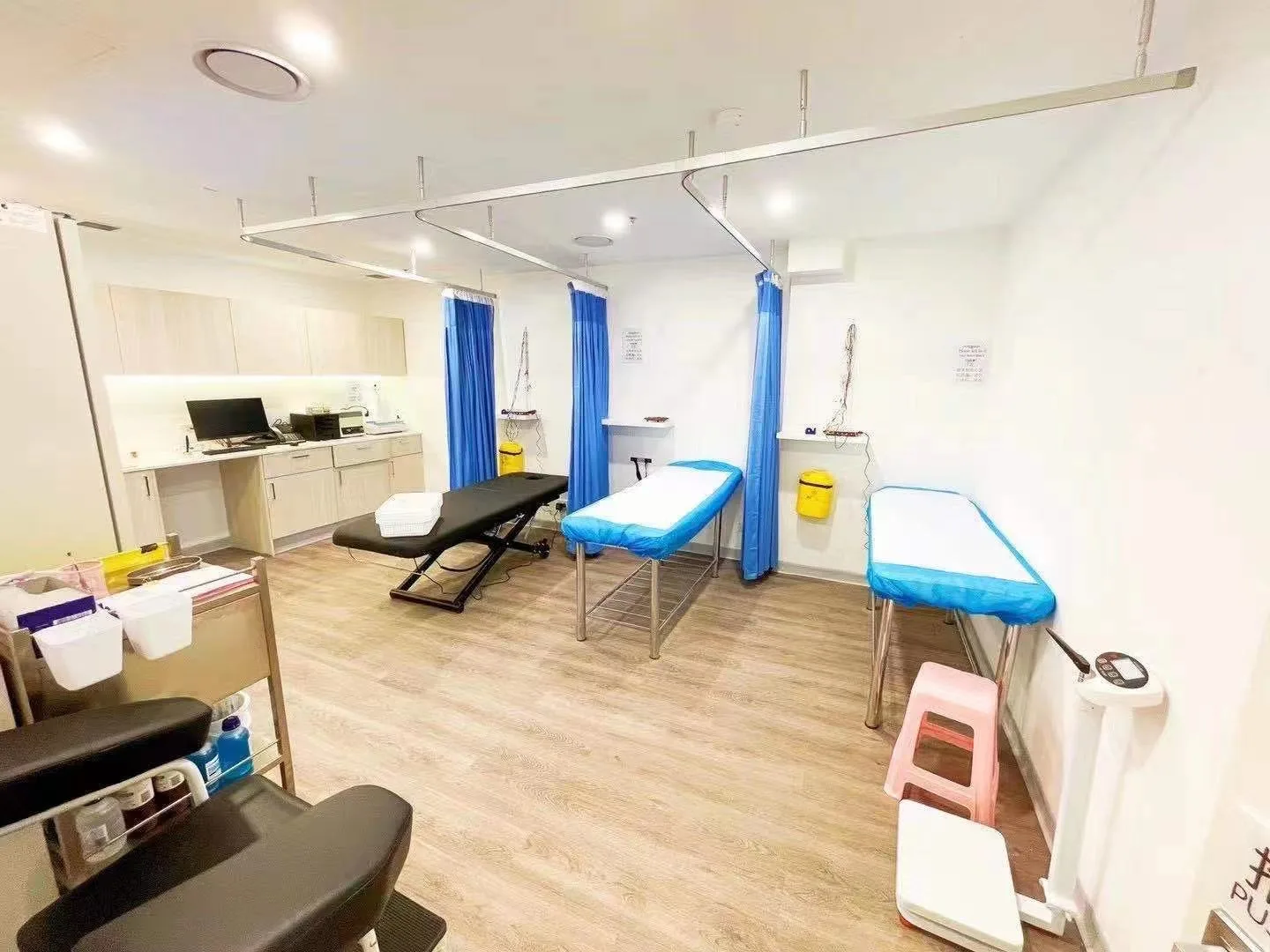 Treatment rooms with three exam beds, blue privacy curtains and timber floor