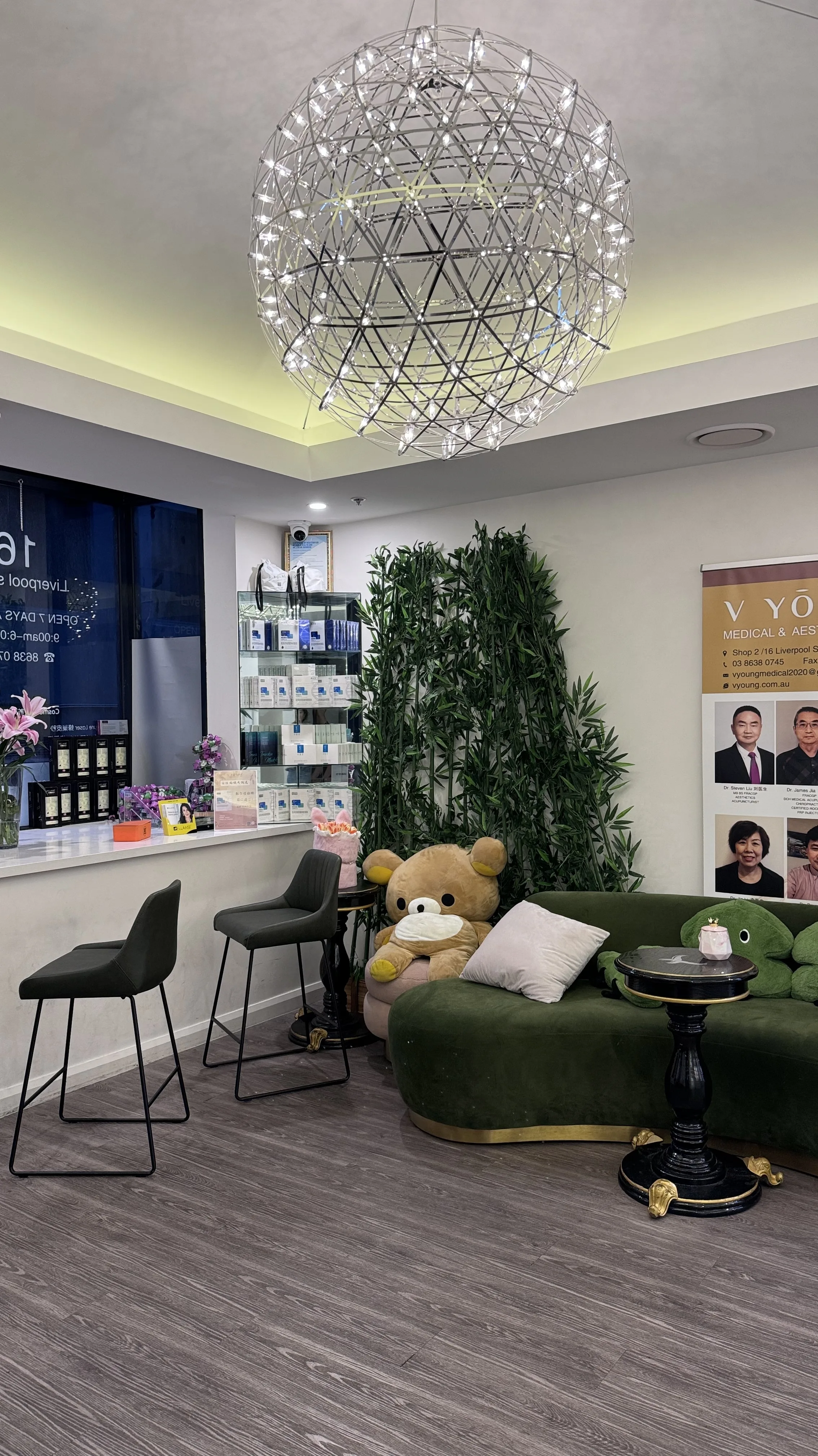 Waiting lounge with giant starburst chandelier, curved green velvet sofa, plush bear and bamboo